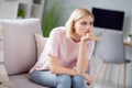 Photo of sad unhappy displeased young woman sit couch bad mood look away sit sofa indoors inside house home