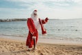 photo of Santa Claus with Christmas sack full of gifts walking on the beach Royalty Free Stock Photo