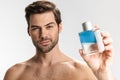 Photo of sassy half-naked man posing and showing perfume