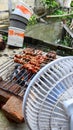 Photo of satay being grilled over charcoal while being fanned