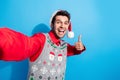 Photo of satisfied funky cool guy wear christmas hat doing selfie showing thumb up approve good job isolated on blue Royalty Free Stock Photo