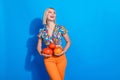 Photo of satisfied girl with bob hair dressed print shirt holding squashes look at sale empty space isolated on blue