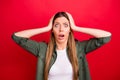 Photo of scared girl having evidently forgotten doing something while isolated with red background