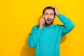 Photo of scared impressed man wear turquoise clothes answering modern device looking empty space isolated yellow color