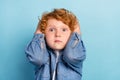 Photo of scared nervous guilty ginger kid touch head speechless wear jeans jacket isolated blue color background