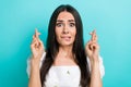 Photo of scared nervous lady wear white blouse biting lip fingers crossed isolated turquoise color background