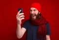Photo of screaming bearded guy, wearing red hat and scarf, using