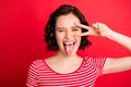 Photo of screaming girl showing her tongue after having eaten hot sauce while isolated with red background