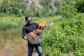 Photo of screaming happy musician against backdrop of summer landscape. young hipster bearded guy holds burning guitar Royalty Free Stock Photo