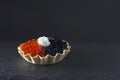 A photo of seafood. Red salmon and black sturgeon caviar with cream cheese in a tartlet on the dark background with copyspace,