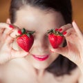 Photo of seductive female holding strawberry near face eyeys, closeup portrait redhead sensual woman biting berry