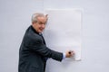 Photo of a senior businessman getting ready to write a message on a white posterboard