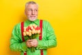 Photo of senior man happy positive smile shy modest present flowers look empty space isolated over yellow color