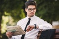 Photo of serious businessman in suit reading newspaper on bench Royalty Free Stock Photo