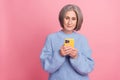 Photo of serious concentrated blogger senior woman bob grey hair use her new samsung phone enjoy watch tiktok app