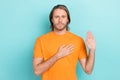 Photo of serious confident guy wear orange t-shirt promising tell only truth isolated teal color background