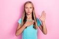 Photo of serious confident little child dressed teal t-shirt rising palm promising telling truth pink color