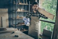 Photo of serious confident man holding wooden block on his shoulder and rolls of blueprints with the other hand standing