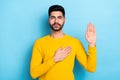 Photo of serious confident man wear yellow sweater promising tell truth isolated blue color background