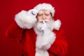 Photo of serious confident retired man wear santa claus costume spectacles asking keep secret finger lips isolated red