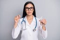 Photo of serious doctor girl hold pill glass water wear specs stethoscope white uniform isolated grey color background Royalty Free Stock Photo