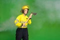 Photo of serious pretty young fire lady workwear yellow helmet holding axe looking empty space isolated green color Royalty Free Stock Photo