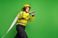 Photo of serious reliable firewoman dressed yellow uniform helmet holding fire hose looking empty space isolated green