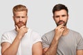 Photo of serious two men hold chins, dressed in casual t shirts, model against white background, being deep in thoughts Royalty Free Stock Photo