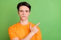 Photo of serious young calm man point finger index empty space information sale isolated on green color background