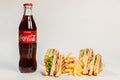 Photo session new menu of coffee house, fresh club sandwich, glass bottle of Coca Cola, french fries, ketchup isolated on white