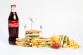 Photo session new menu of coffee house, fresh club sandwich, glass bottle of Coca Cola, french fries, ketchup isolated on white