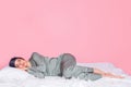 Photo of shiny adorable young lady sleepwear smiling lying blanket closed eyes isolated pastel pink color background