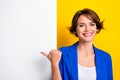 Photo of shiny cheerful lady dressed blue blazer pointing thumb white wall placard empty space isolated yellow color