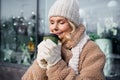 Photo of shiny cute woman wear beige coat closed eyes enjoying hot coffee aroma smiling outside urban city street Royalty Free Stock Photo