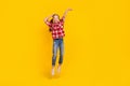 Photo of shiny impressed schoolkid dressed plaid shirt jumping high measuring empty space isolated yellow color