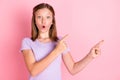 Photo of shocked amazed little girl point fingers empty space promoter sale isolated on pink color background