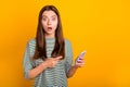 Photo of shocked disquieted girl dissatisfied with her new phone while isolated with vivid yellow background Royalty Free Stock Photo