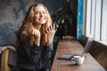 Beautiful young pretty woman sitting in cafe indoors using laptop computer and mobile phone Royalty Free Stock Photo