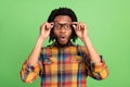 Photo of shocked excited dark skin man wear plaid shirt arms spectacles open mouth green color background