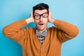 Photo of shocked scared young man hold hand cover ears afraid wear glasses isolated on blue color background