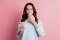 Photo of shocked voiceless adorable girl use phone palm cover mouth on pink background