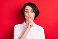 Photo of shocked young woman hold finger mouth lips secret silence isolated on red color background