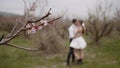 Photo shoot on the background of an orchid.Action. The bride and groom in a short white dress and a veil who kiss and