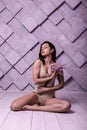 Flirtatious gorgeous lady sitting over lilac background amid photo shooting