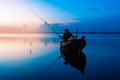 Photo shot fisherman throwing fishing net on the lake. Silhouette of fisherman with fishing net in morning sunshine. Royalty Free Stock Photo