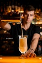 photo shot of the process of pouring cocktail from shaker with strainer into glass