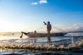 Photo shot of water spatter from fisherman while throwing fishing net on the lake. Silhouette of fisherman with fishing net in mo Royalty Free Stock Photo