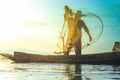 Photo shot of water spatter from fisherman while throwing fishing net on the lake. Silhouette of fisherman with fishing net in mo Royalty Free Stock Photo