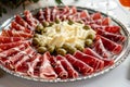 This photo showcases a platter filled with a variety of meats, cheeses, and olives, A platter of Jamon Iberico with cheese and