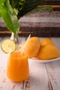 Mango mocktail and plate of mango. Vase with tropical leaves on left Royalty Free Stock Photo